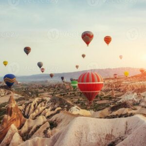 Hot air balloons floating over Red Valley at sunrise