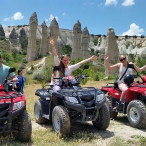 Group of travelers on an ATV sunset tour in Cappadocia, kicking up dust trails