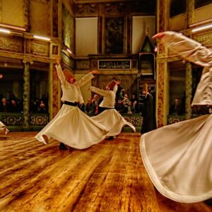 Whirling Dervish performers under atmospheric lighting, creating a mesmerizing spiritual experience in Cappadocia