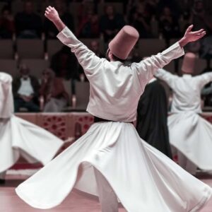 Whirling Dervishes performing the Sufi dance in a historic stone-carved hall in Cappadocia, Turkey